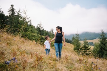 Naklejka premium Young mom with baby boy travelling. Mother on hiking adventure with child, family trip in mountains. National Park. Hike with children. Active summer holidays.
