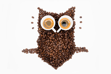 Owl made of roasted coffee beans and two cups. A symbol for night people.