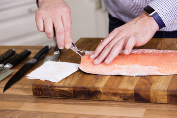 Close up of chef removing fish bone from salmon.