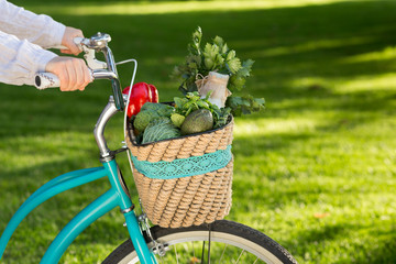 Woman riding on bike with fresh farm vegetables