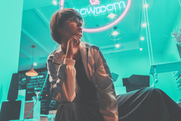 Fashion tomboy teen hipster short hairstyle gen z girl wear stylish clothes glasses sitting on...