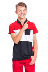 Portrait of happy teen boy pointing finger away at copy space, isolated on white background. Teenager pointing finger at something. Cute smiling child looking at camera.