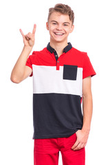 Portrait of teen boy making Rock gesture, isolated on white background. Handsome caucasian young teenager showing horns up gesture. Happy cute child smiling and doing heavy metal rock sign.