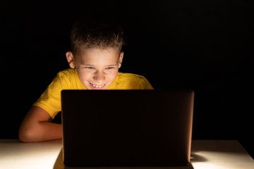 Laughing teenager looking at laptop screen sitting in the dark