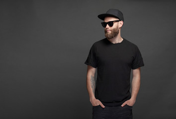 Hipster handsome male model with beard wearing black blank t-shirt with space for your logo or...