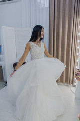 Beautiful girl tries on a wedding dress in a bridal salon.