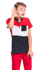 Portrait of teen boy holds his hand near his ear and listening something, isolated on white background. Cute caucasian young teenager overhears, listening an hearing to rumor or gossip.