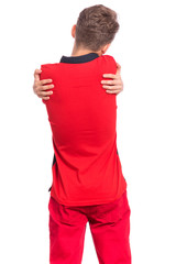 Back view. Self love and self care. Portrait of teen boy Hugging oneself, isolated on white background. Cute caucasian young teenager in red. Happy funny child - rear view.