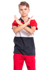 Portrait of teen boy doing stop sign with crossed hands, isolated on white background. Cute caucasian young teenager making stop gesture with serious facial expression. Child looking at camera.