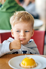 Fototapeta premium Two year old boy eating dessert in cafe