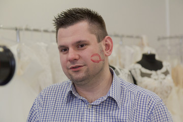 Young man with lipstick on his cheek in a wedding salon.