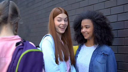 Female teenagers laughing at new student passing by, school rejection, offend