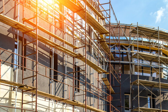 Extensive scaffolding providing platforms for work in progress on a new apartment block,Tall building under construction with scaffolds,Construction Site of New Building