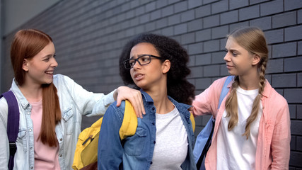 College students stopping frightened black teenager in school backyard, bullying