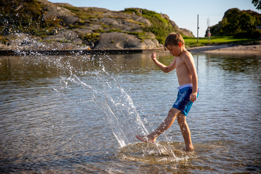 Boy kicking and playing in water in sidelight