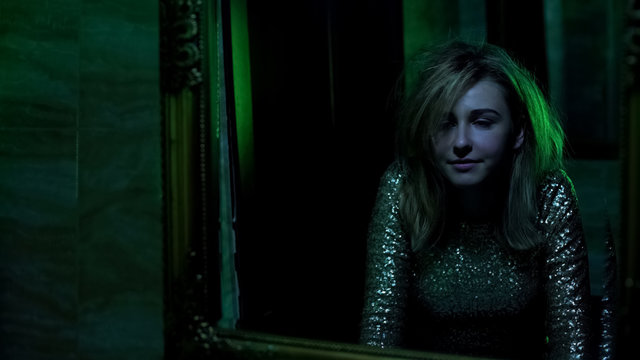 Woman looking in mirror, euphoria after snorting cocaine in night club toilet