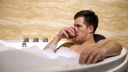 Nervous businessman trying to relax taking aroma bathtub and drinking rum