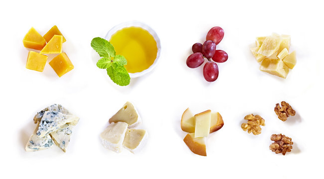 Different type of cheese with honey, grape, nuts on white background. Top view. Blue cheese, cheddar, parmesan, maasdam and brie cheese slices