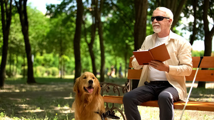Blind man feels happy reading book, resting with dog, socially secure life