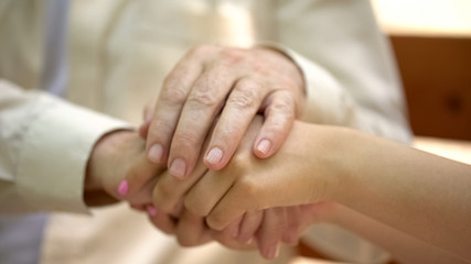 Senior man holding hand of young woman, support and care of relative concept