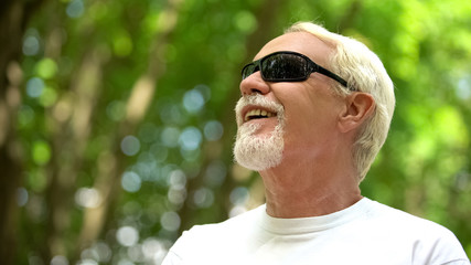 Visually impaired man in sunglasses listening nature sounds, heightened senses