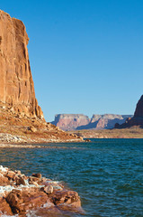 The tall re rock cliff along the water of the big lake powell. 
