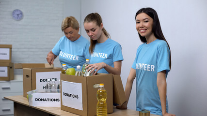 Volunteers putting food in donation boxes, charity funds to help people in need
