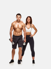 Fototapeta na wymiar Portrait of strong healthy man and woman posing with dumbbells