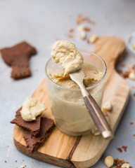 Homemade peanut butter in a jar and chocolate cookies on a cutting board on a concrete background. Perfect breakfast