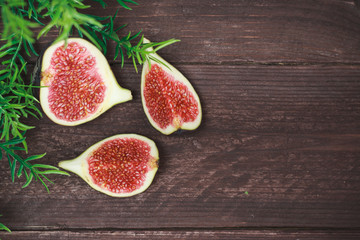 Fig fruits. Still life of figs on a dark wooden table. Cut fruit into pieces. Slices of juicy fruit.