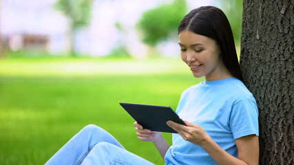 Fototapeta premium Attractive young woman watching tablet video sitting park, online application