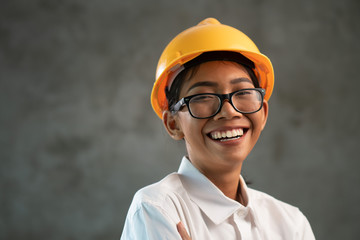 Portrait of smiling attractive Asian woman engineer over concrete wall background