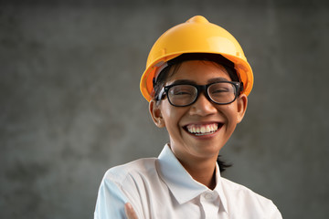 Portrait of smiling attractive Asian woman engineer over concrete wall background