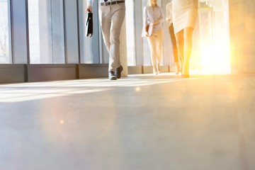 Business people walking in office hall with yellow lens flare in background