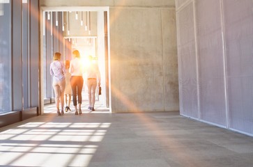 Business people walking in office hall with yellow lens flare in background