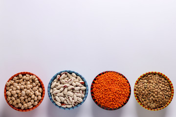 Red and brown lentils, chickpeas and white beans are legumes that contain a lot of protein are located on a white background in bowls, horizontal orientation