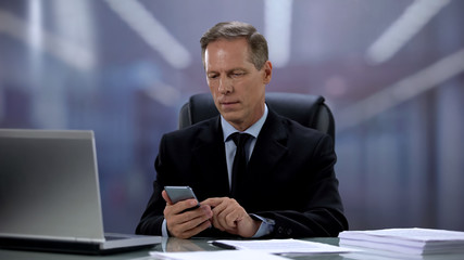 Businessman texting cellphone with client at workplace with laptop, technologies