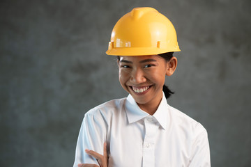 Portrait of smiling attractive Asian woman engineer over concrete wall background