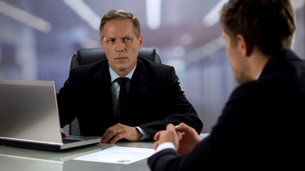 Angry boss looking at candidate, failed job interview, cv lying on table
