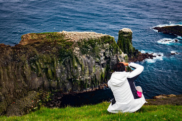 Unidentified tourist takes photos to gannet colony