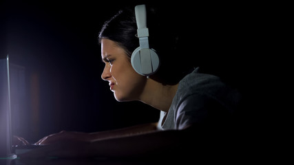 Upset girl in headset looking at laptop screen, error of program, virus attack