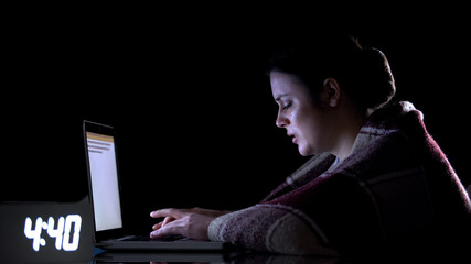 Crying female freelancer working on laptop at night, hard labor conditions