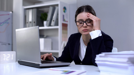 Fototapeta premium Businesswoman typing on laptop and suffering headache as result of workload