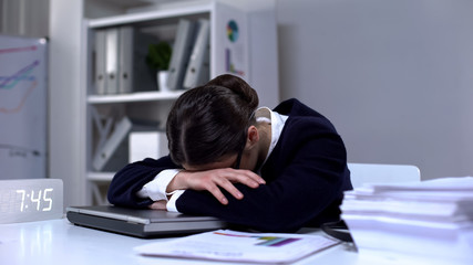 Overloaded female lying on laptop sleeping in office as result of workload