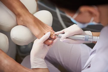 Foto op Plexiglas Pedicure Pedicure die elektrische nagelboor gebruikt tijdens pedicure voor jonge dame