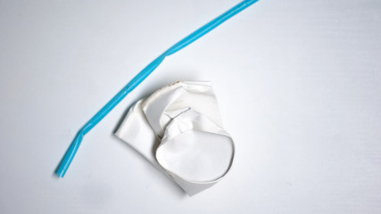 Crumpled coffee cup and plastic straw lying on white background, recycling