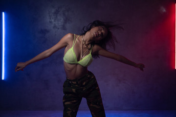 Young beautiful fashion Asian girl dancer wearing stylish clothes dancing in studio with neon lights