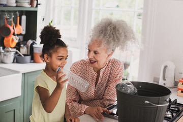 Grandmother recycling at home with granddaughter