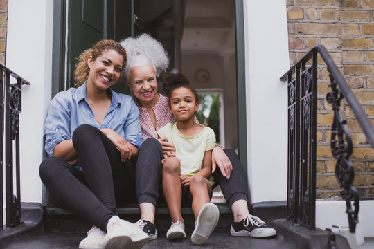 Three generations of women sitting outside family home