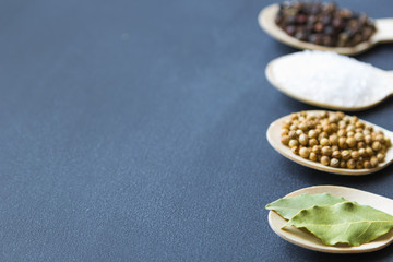 composition of assorted spices in wooden spoons on a dark background. bay leaf in the front. close up